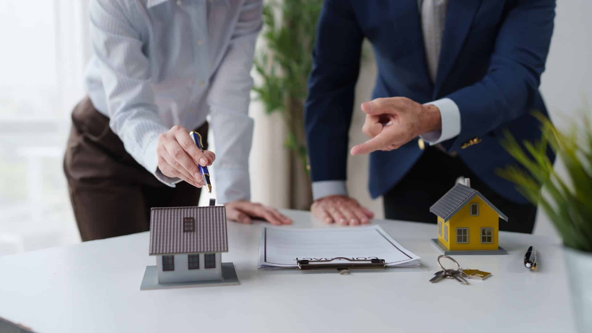 House models beside a turnover contract on a desk