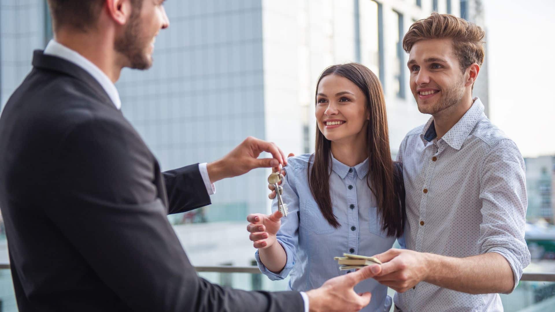 Leasing agent handing house keys to a new tenant outdoors