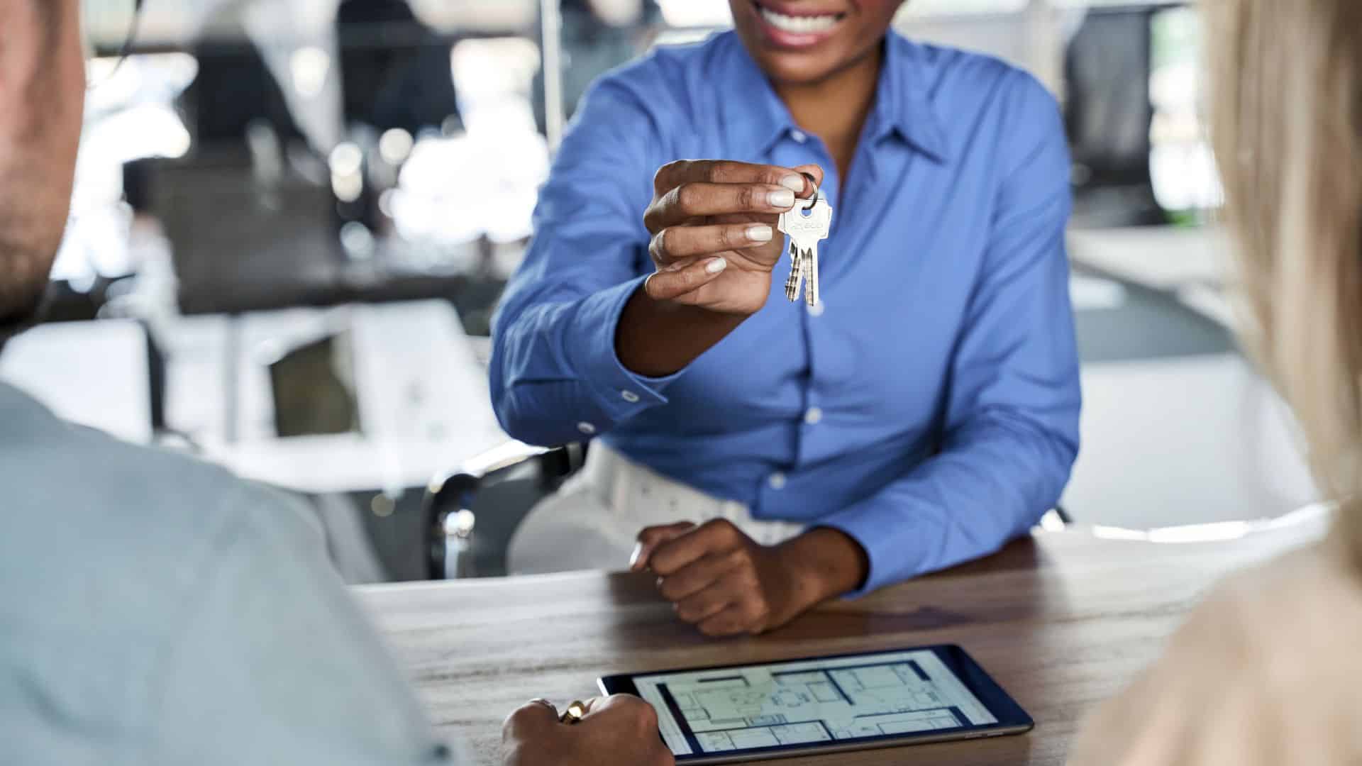 Key handoff to a tenant with a tablet showing screening approval
